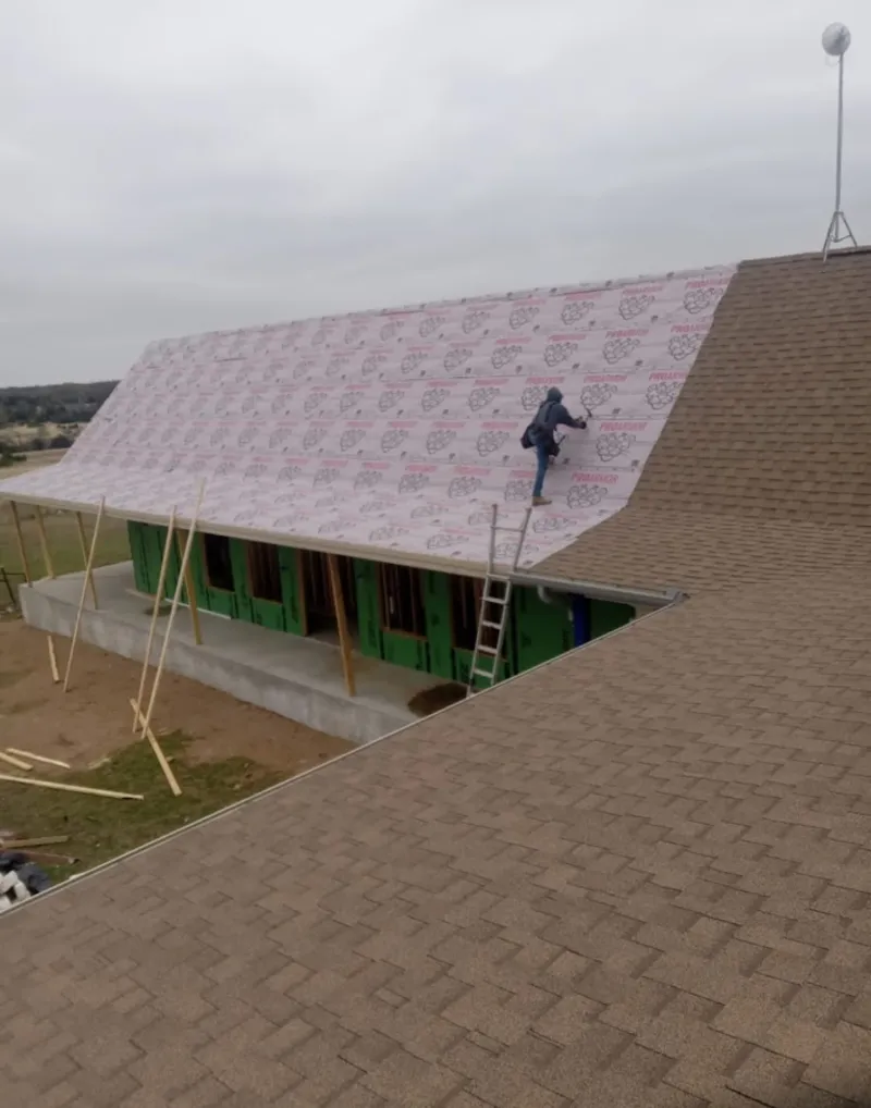 Worker preparing underlayment for a metal roof installation in Bennington